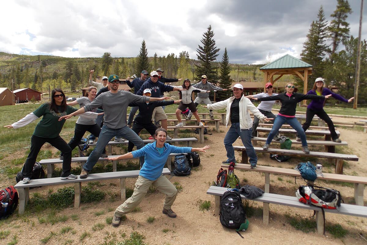 Group of workshop participants outdoors standing on bleachers showing balanced poses as if they are surfing